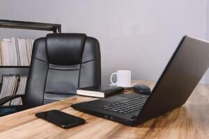 un oficina con un silla un escritorio un ordenador portátil un teléfono un cuaderno y un taza de café. concepto antecedentes. foto