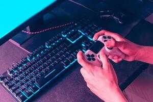 hands holding a joystick to play a video game in front of a monitor. photo