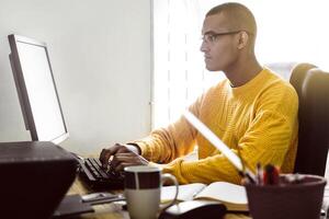 latin american typing or working on his desktop computer. remote work concept. photo