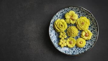 Thai dessert in various flower shaped, warm color tone, yellow mango flavor in antique pattern plate, Sam Pan Nee traditional Thai handcraft snack in Dark background photo