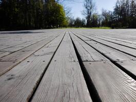 Boardwalk by the garden, wooden plank, decking, walkway, path or terrace, low angle view image of patio deck with blurred green background, copy space photo