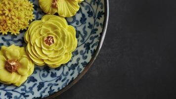 Thai dessert in various flower shaped, warm color tone, yellow mango flavor in antique pattern plate, Sam Pan Nee traditional Thai handcraft snack in Dark background photo