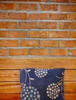 Hand embroidered fabric cushions on wooden bench with red brick wall as background, rest relax corner, contrast color design, home decoration photo