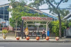 a bus stop with several people waiting for the city bus to arrive, Indonesia, 2 March 2024. photo