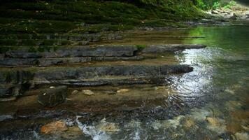 Clear stream running through stone boulders. Creative. Calm river flowing on stone bottom in slow motion. video