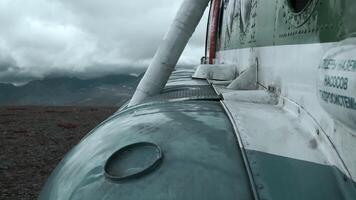 Close up of old rusty airplane on a hill top. Clip. Aircraft exterior details with heavy clouds and mountains on the background. video