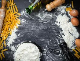 Raw homemade pasta and ingredients for pasta on wooden background. Top view photo