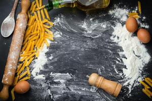 Raw homemade pasta and ingredients for pasta on wooden background. Top view photo