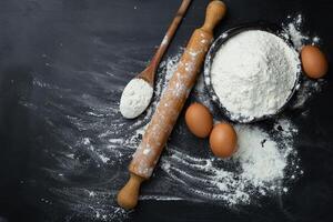 Baking background. Flour and rolling pin on dark table with copy space, top view. World Bread Day photo