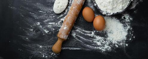 Banner. Baking background with free space for your text. Rolling pin and flour on black table. Copy space. Top view photo