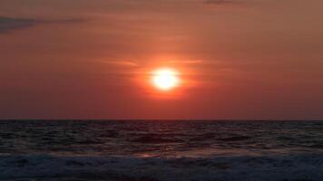 Beautiful rolling waves on background of setting sun. Action. Beautiful foaming waves move on background of bright sun at sunset. Orange sun over sea horizon with waves video