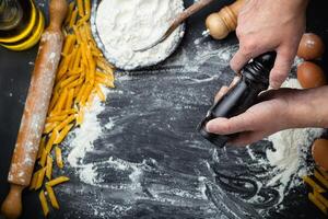 Hand holding wooden grinder. Preparation pasta, pizza, bread on black background. photo