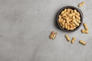 Peanut in a bowl on play stone background top view copy space. Healthy snack food. photo