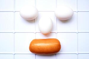 Smiling three eggs and sausage on a plastic surface photo