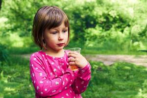 Cute serious girl with a glass of drink on a picnic in nature photo