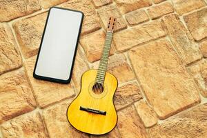 acústico guitarra y teléfono en amarillo marrón pavimento foto