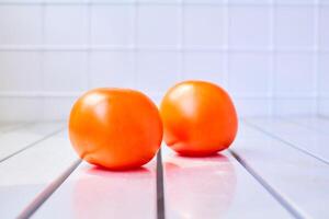 Two red ripe tomatoes on a striped white surface photo