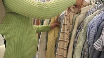 fechar acima do uma mulher escolhendo roupas em uma cabide dentro uma Shopping adiante do eid al fitr video
