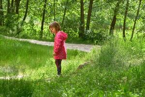 Serious curious cute dreaming girl child walks among the trees in forest park photo