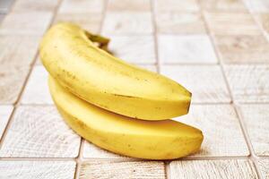 dos maduro bananas en un a cuadros de madera superficie foto