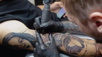 el tatuaje artista sorteos pequeño detalles en el fotografía. tatuaje con un mujer cara en un del hombre brazo video