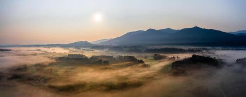 Sunset Panorama with drone at the Bavarian Alps. Mist and fog at the ground photo