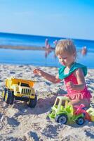 Happy toddler child playing on the beach with toy car.Summer vacation trip concept. Vertical photo. photo