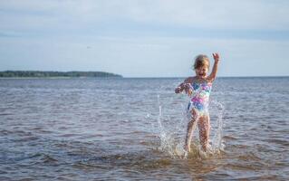 joven contento niño niña de europeo apariencia años de 6 6 teniendo divertido en agua en el playa y salpicaduras, tropicales verano vocaciones,vacaciones.a niño disfruta el familia.mar Días festivos concepto.copiar espacio. foto