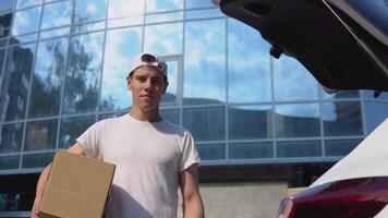 Moving and delivery of manufactured goods. An employee holds a box in his hands and stands next to a car filled with parcels video