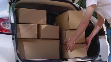 Moving and delivery of manufactured goods. The loader puts craft boxes in the trunk of the car video