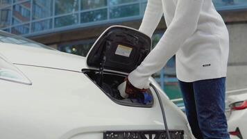 A young african american man connects an electric car to the charger. The process of connecting the electric car to the charger. Close-up view video