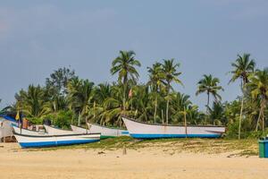 old fishing boats in sand on ocean in India on blue sky background photo