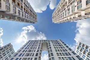view from below into blue sky with clouds of large modern skyscraper residential complex with arch photo