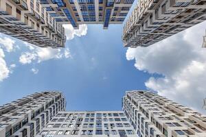 view from below into blue sky with clouds of large modern skyscraper residential complex with arch photo