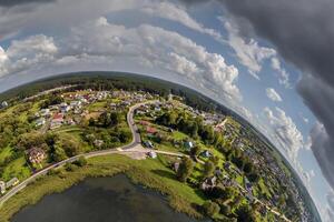 Aerial view from high altitude tiny planet in sky with clouds overlooking old town, urban development, buildings and crossroads. Transformation of spherical 360 panorama in abstract aerial view. photo