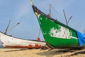 old fishing boats in sand on ocean in India on blue sky background photo