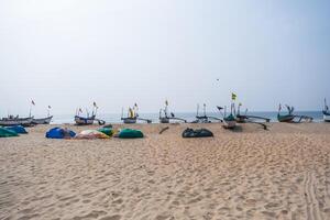 old fishing boats in sand on ocean in India on blue sky background photo