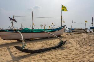 old fishing boats in sand on ocean in India on blue sky background photo