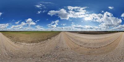 hdri 360 panorama on gravel road among fields in spring evening with awesome clouds in equirectangular full seamless spherical projection, for VR AR virtual reality content photo