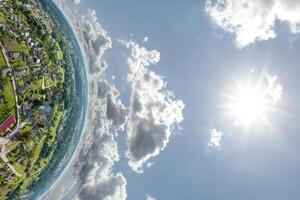 Aerial view from high altitude tiny planet in sky with clouds overlooking old town, urban development, buildings and crossroads. Transformation of spherical 360 panorama in abstract aerial view. photo