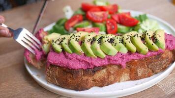 Person enjoys sandwich with avocado and hummus on plate video