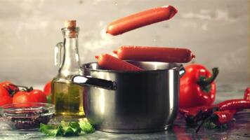 Super slow motion sausages fall into a pan with water spray. On a gray background.Filmed on a high-speed camera at 1000 fps. High quality FullHD footage video