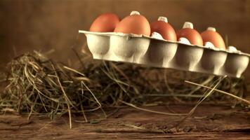 A super slow motion box with fresh raw eggs falls on the table. On a wooden background. Filmed on a high-speed camera at 1000 fps. video