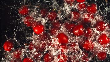 Super slow motion ripe cherry falls into the water with splashes. On a black background.Filmed on a high-speed camera at 1000 fps. High quality FullHD footage video