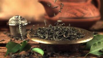 Super slow motion dry tea leaves fall into the plate. On a wooden background. Filmed on a high-speed camera at 1000 fps.High quality FullHD footage video