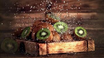 super langzaam beweging Aan de kiwi in de houten dienblad druppels water. Aan een houten achtergrond.gefilmd Aan een hoge snelheid camera Bij 1000 fps. hoog kwaliteit full HD beeldmateriaal video