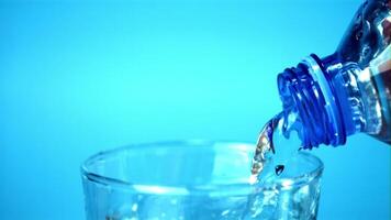 Super slow motion water pours from bottle to glass. On a blue background. Filmed on a high-speed camera at 1000 fps. video