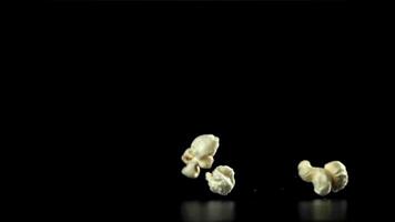 Popcorn falls on the table. On a black background. Filmed on a high-speed camera at 1000 fps. High quality FullHD footage video