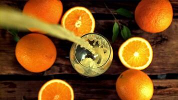 súper lento movimiento en el vaso torbellino vierte naranja jugo. en un de madera fondo.filmado en un alta velocidad cámara a 1000 fps. video