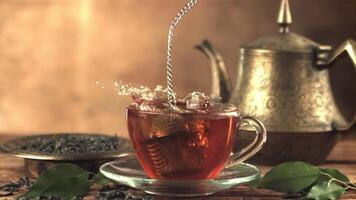 Super slow motion in a cup of tea drops a strainer with splashes. On a brown background.Filmed on a high-speed camera at 1000 fps. video